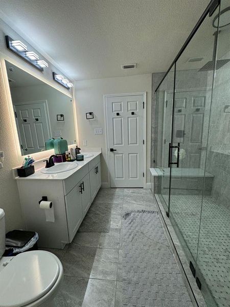 Bathroom with a shower with shower door, oversized vanity, and tile floors