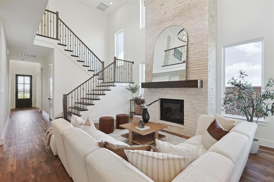 Living room with a high ceiling, dark hardwood / wood-style floors, and a brick fireplace