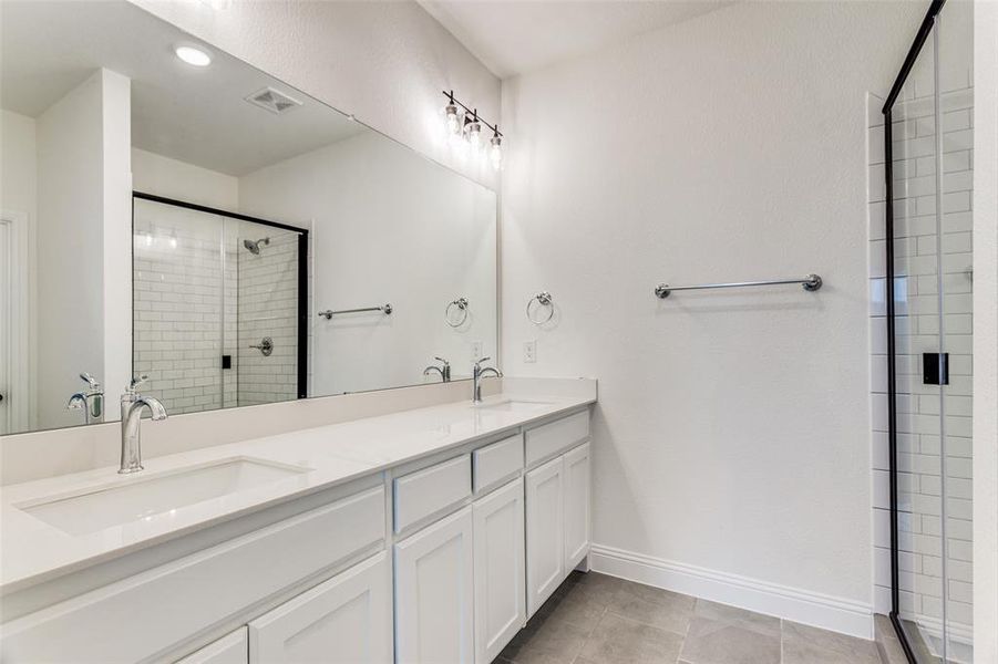 Bathroom featuring walk in shower, tile flooring, and dual vanity
