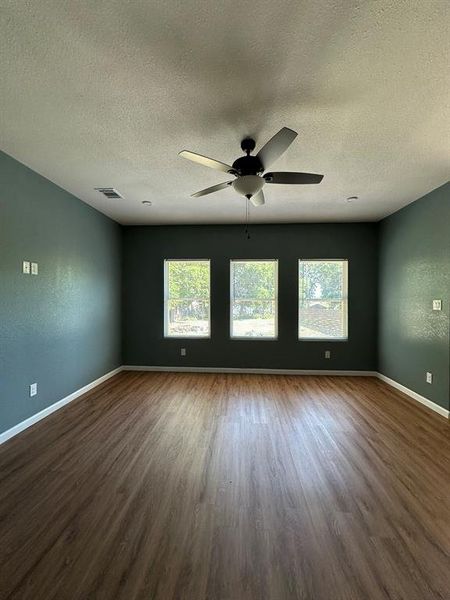 Unfurnished room featuring dark wood-type flooring, ceiling fan, and a textured ceiling