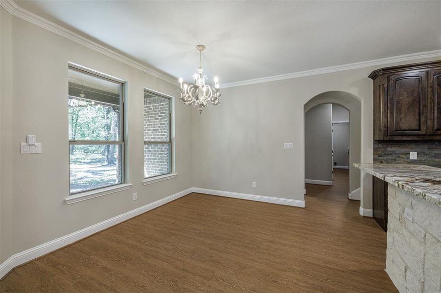 Unfurnished dining area with ornamental molding, a chandelier, and dark hardwood / wood-style flooring