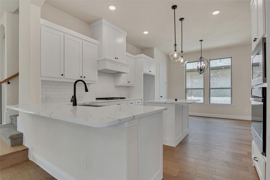 Kitchen featuring white cabinets, light hardwood / wood-style flooring, tasteful backsplash, and kitchen peninsula