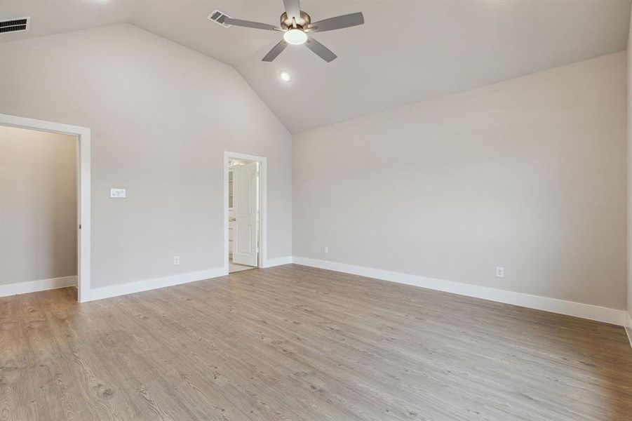 Spare room with high vaulted ceiling, ceiling fan, and light hardwood / wood-style floors