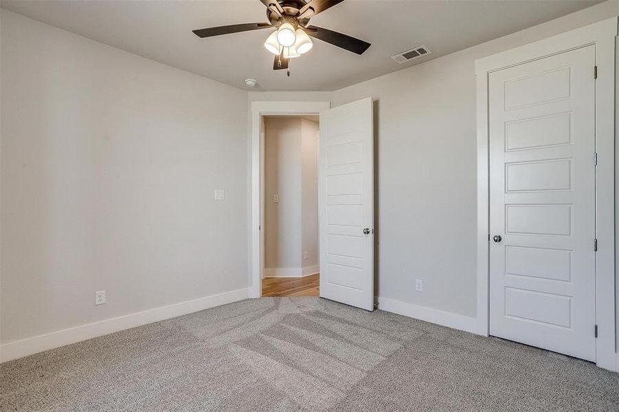 Unfurnished bedroom featuring light carpet and ceiling fan