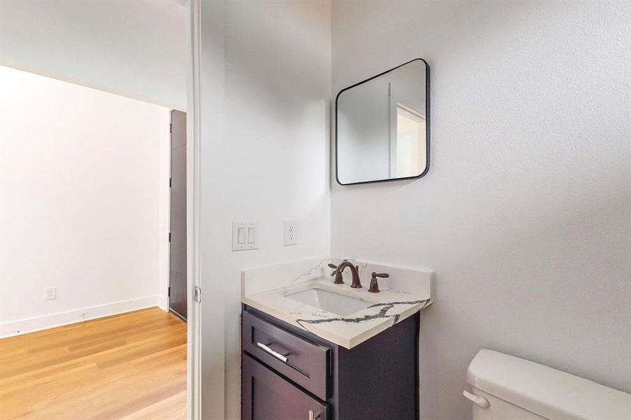 Bathroom featuring toilet, vanity, and wood-type flooring