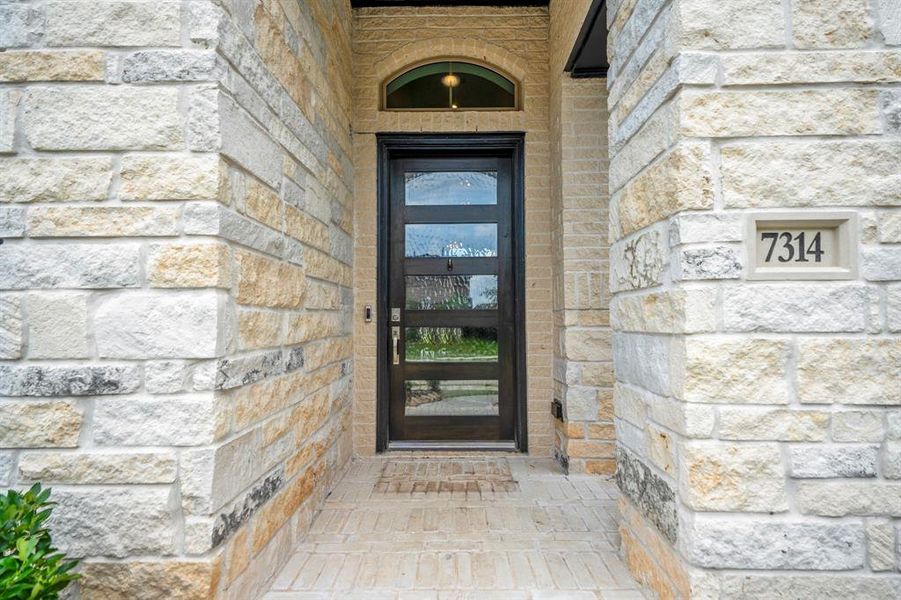 Approaching the front door you will see the beautiful brick and stone elevation, covered front porch, and an 8ft stained contemporary door! This home includes keyless entry and a smart door bell.
