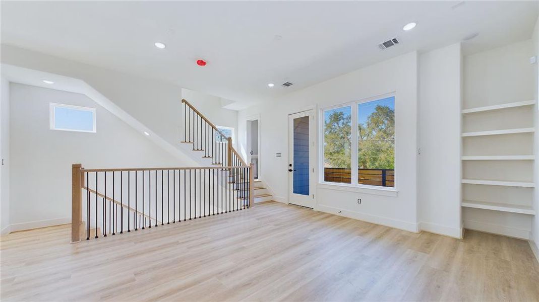 Alternate view of the second-floor living area highlights access to your private balcony. Built-in shelving on the right adds a stylish touch while maximizing storage space.