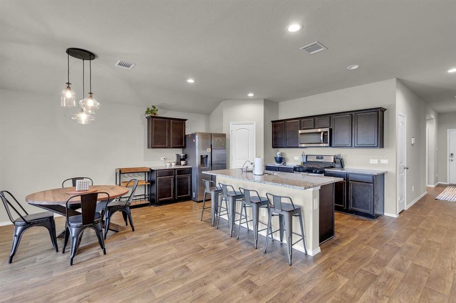 Another view of the kitchen and dining area highlights the open-concept design, showcasing the conveniently located pantry and abundant cabinetry for storage. The well-appointed cooking area is perfect for meal prep, making it easy to entertain while staying connected with guests in the dining space.