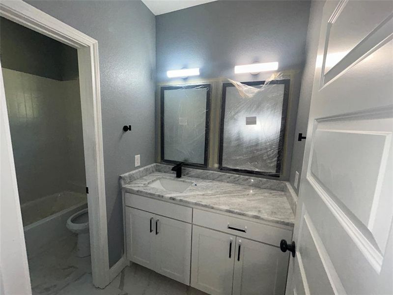 Full bathroom featuring tile patterned flooring, toilet, vanity, and tub / shower combination