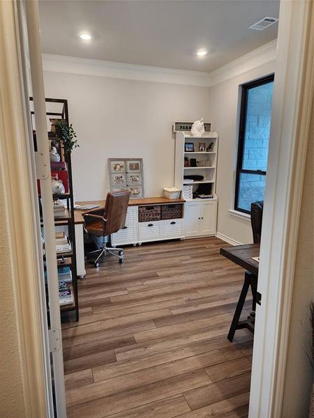 Office area with ornamental molding and hardwood / wood-style flooring