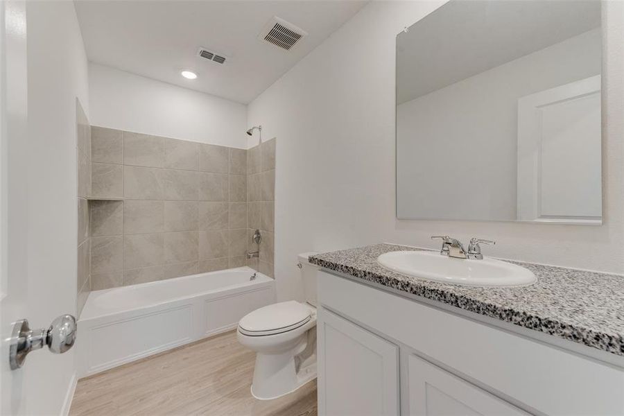 Full bathroom featuring tiled shower / bath, vanity, toilet, and wood-type flooring