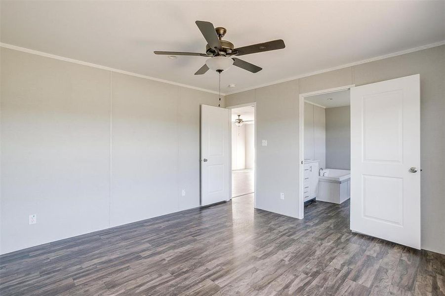 Unfurnished bedroom with crown molding, dark wood-type flooring, ensuite bathroom, and ceiling fan