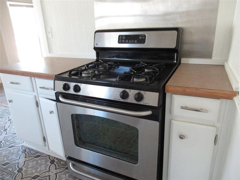 Kitchen featuring stainless steel gas range oven and white cabinets