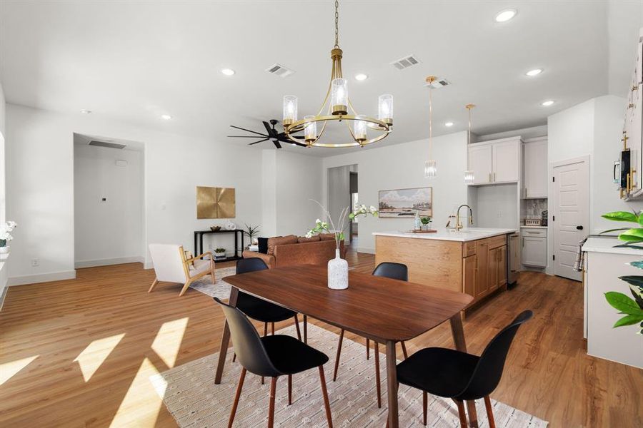 Dining space with ceiling fan with notable chandelier, light hardwood / wood-style floors, and sink