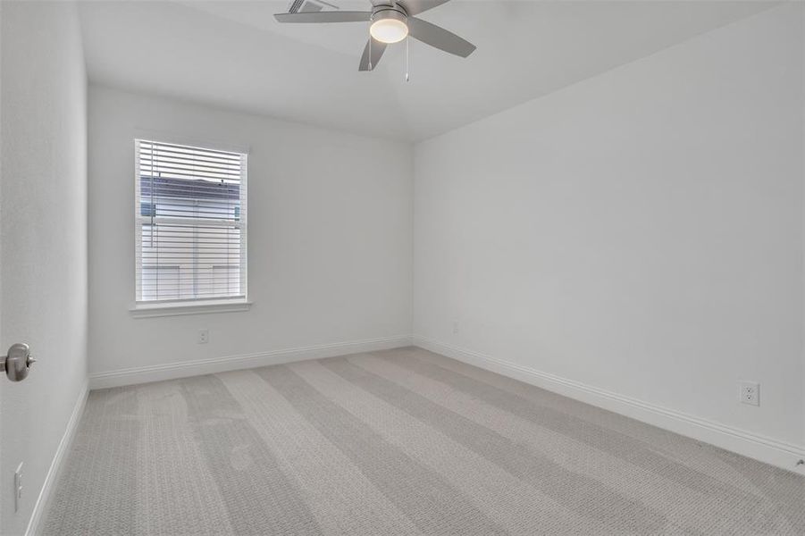 Carpeted empty room featuring ceiling fan