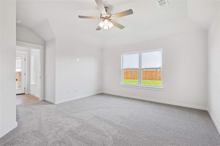 Carpeted empty room with ceiling fan and vaulted ceiling