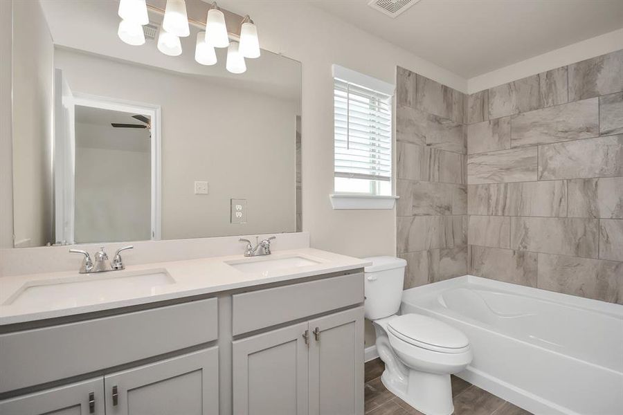 Melt away the day's stress in this inviting primary bathroom. The spacious shower/bathtub combo offers both flexibility and relaxation, while the ample counter space and storage cabinets ensure everything has its place. **This image is from another Saratoga Home with similar floor plan and finishes, not the Brittany floorplan.**