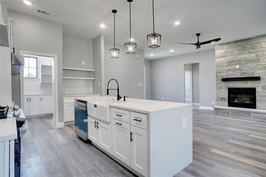 Kitchen featuring white cabinets, light hardwood / wood-style floors, hanging light fixtures, ceiling fan, and sink