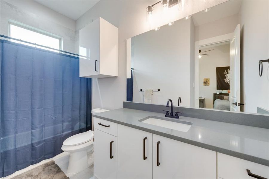 Full bathroom featuring vanity, toilet, ceiling fan, and shower / bathtub combination with curtain