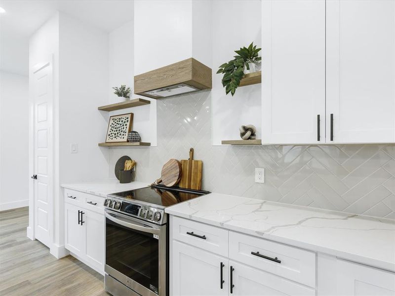 Kitchen featuring white cabinets, decorative backsplash, light wood-type flooring, electric range, and custom range hood