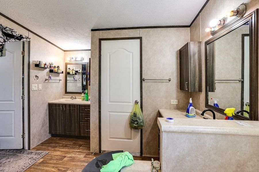 Bathroom with a textured ceiling, ornamental molding, vanity, and hardwood / wood-style floors