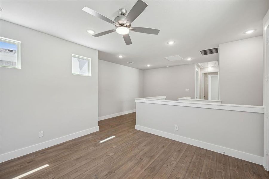 Empty room featuring ceiling fan and dark hardwood / wood-style flooring