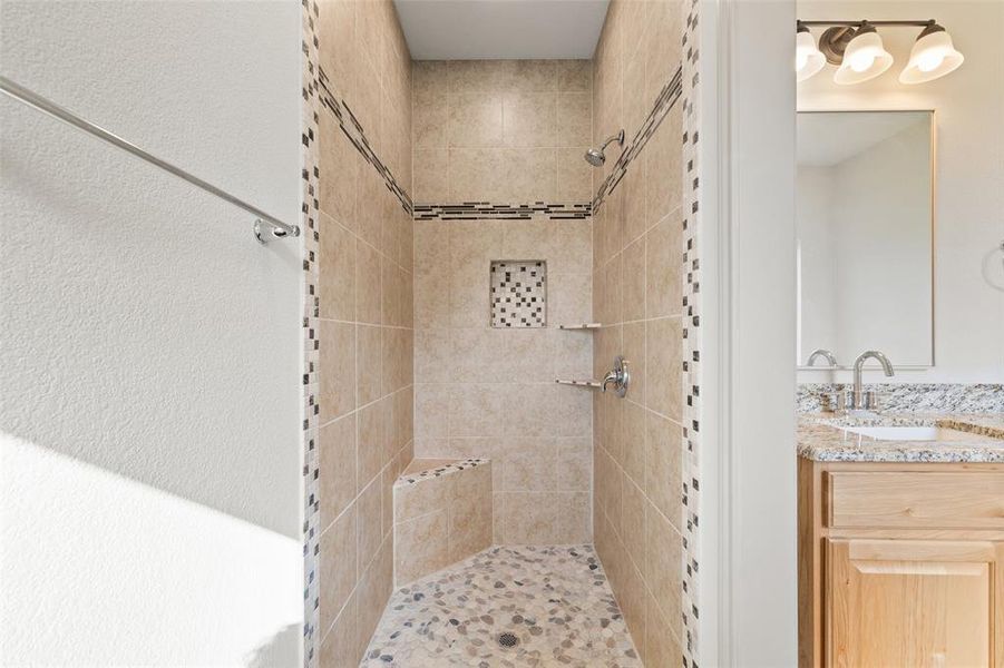 Bathroom with tiled shower and vanity