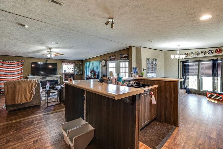 Kitchen featuring a center island with sink, lofted ceiling, sink, and dark hardwood / wood-style flooring