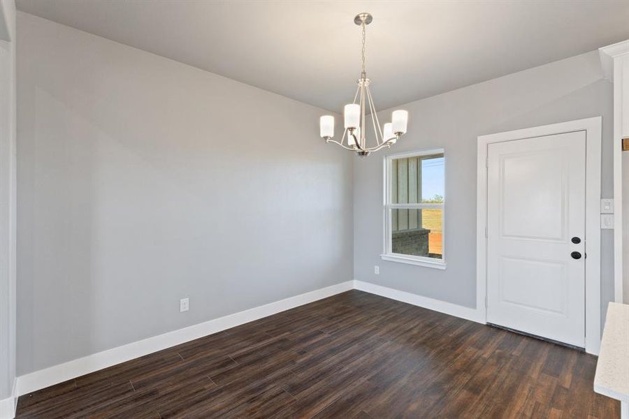 Spare room with dark hardwood / wood-style flooring and a notable chandelier