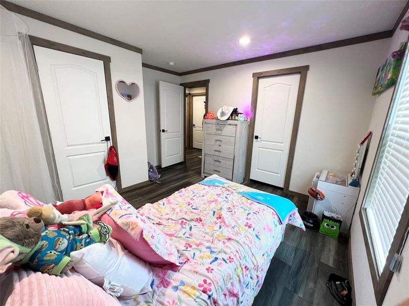 Bedroom with dark wood-type flooring and crown molding