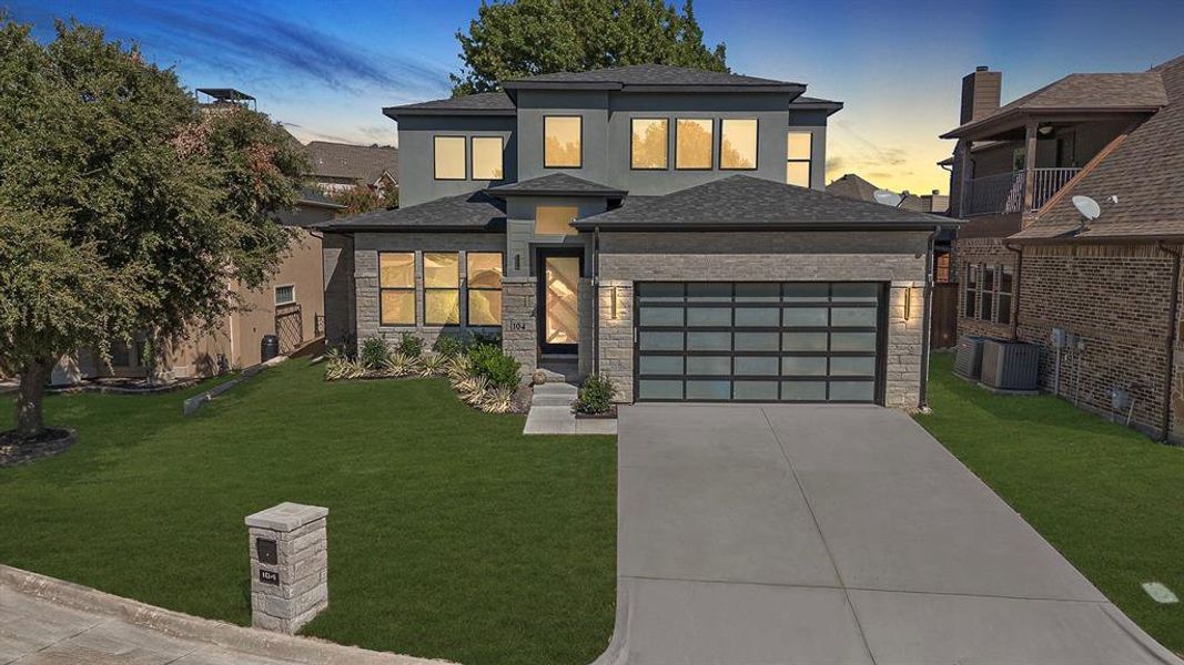 View of front of property with a lawn, cooling unit, and a garage