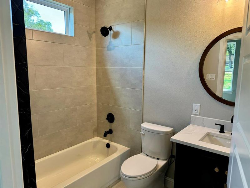 Full bathroom with tiled shower / bath, vanity, and toilet