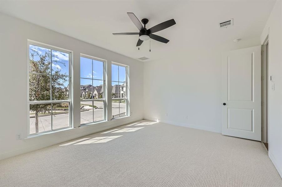 Carpeted empty room featuring ceiling fan