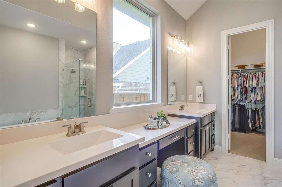 Bathroom featuring a shower with shower door, vanity, a healthy amount of sunlight, and lofted ceiling