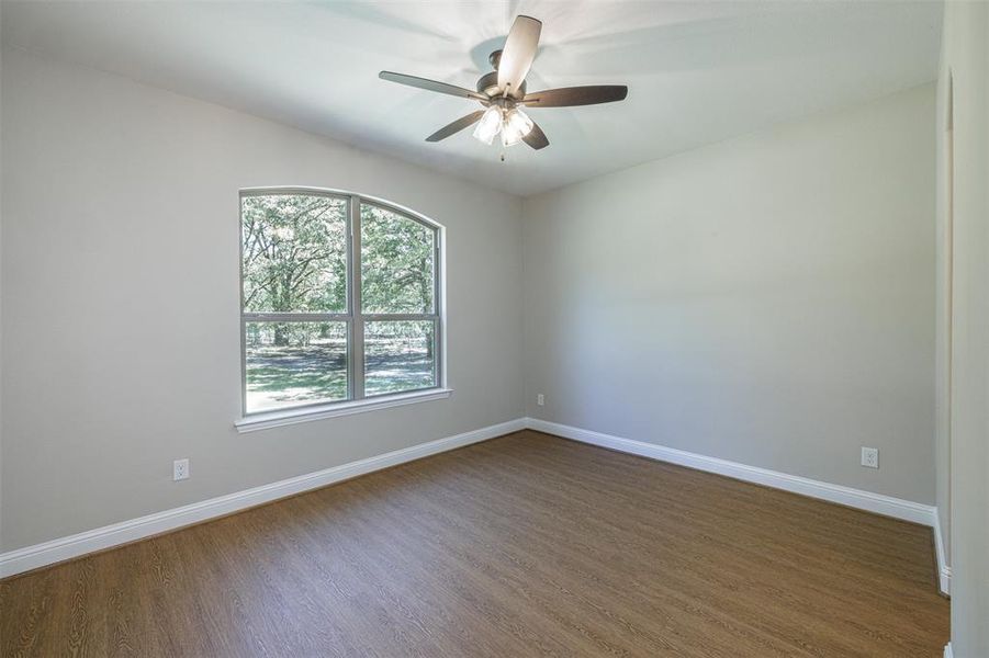 Unfurnished room featuring ceiling fan, dark hardwood / wood-style floors, and a healthy amount of sunlight