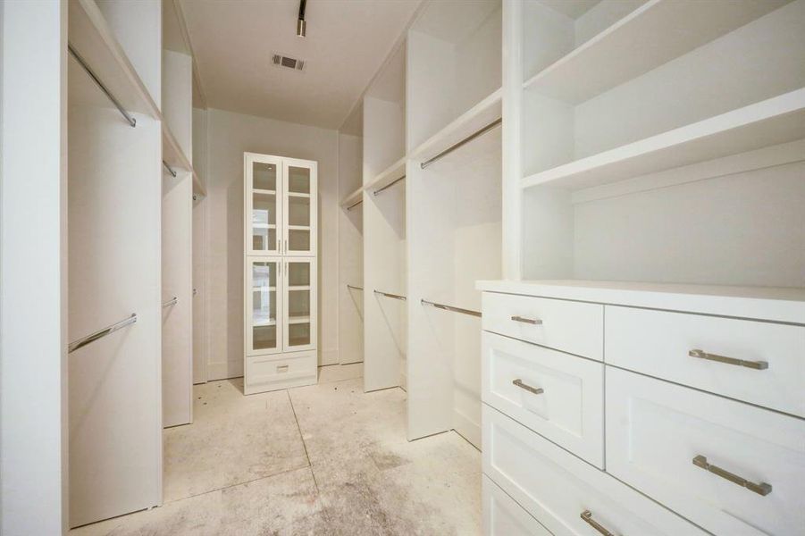 This is just ONE of the 2 walk in closets in the primary suite! With excellent storage options this closet is designed with rods, built in drawers,a glass front cabinet and track lighting!