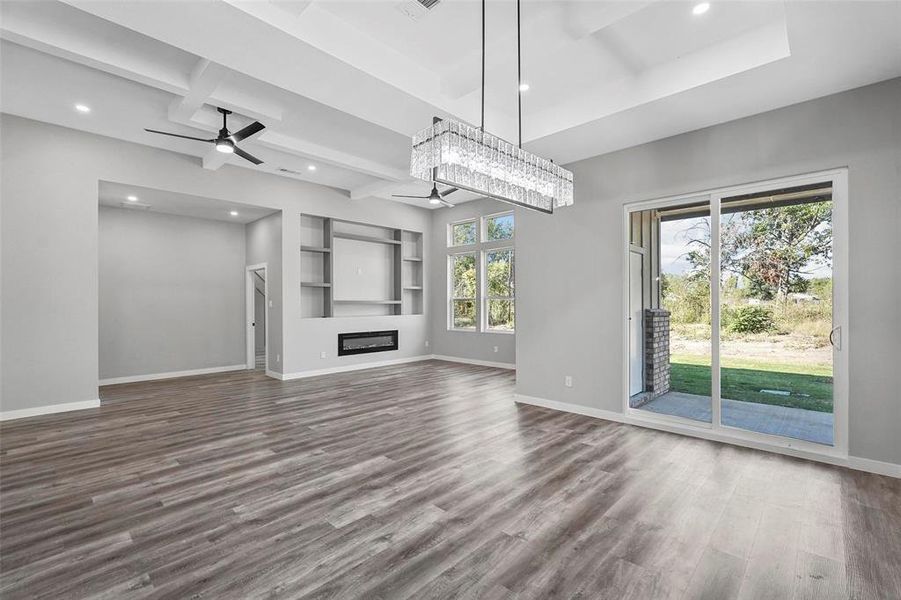 Unfurnished living room featuring hardwood / wood-style floors, ceiling fan, and beam ceiling