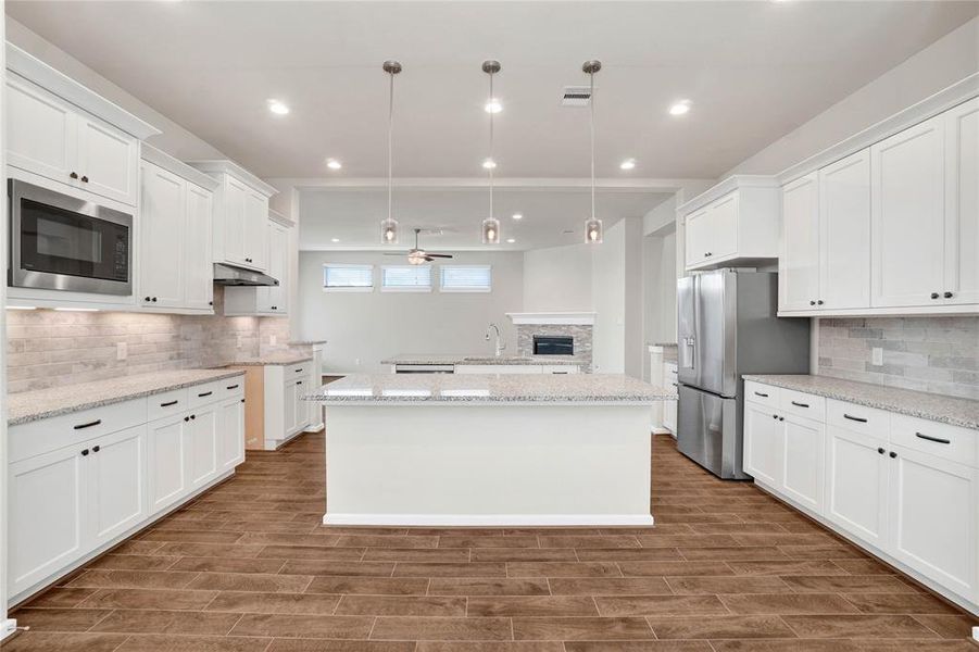 Double the counter space and cabinets with this elevated kitchen. It features two large islands, recessed lighting, and a view of the living area, perfect for entertaining. The herringbone tile flooring adds a touch of elegance.