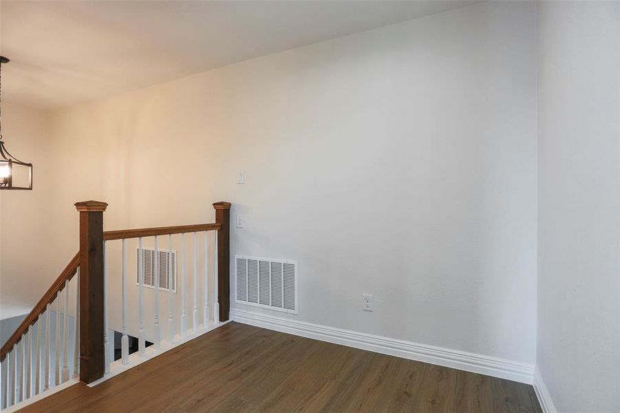 Empty room with a notable chandelier and dark hardwood / wood-style floors