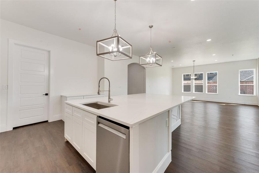 Kitchen featuring sink, pendant lighting, white cabinetry, a center island with sink, and dishwasher