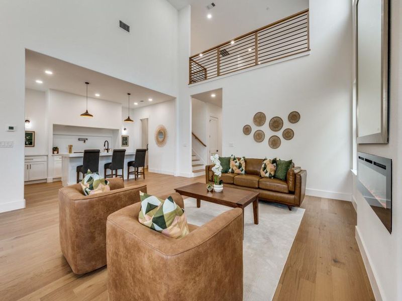 Living room with a high ceiling, light wood-type flooring, and sink