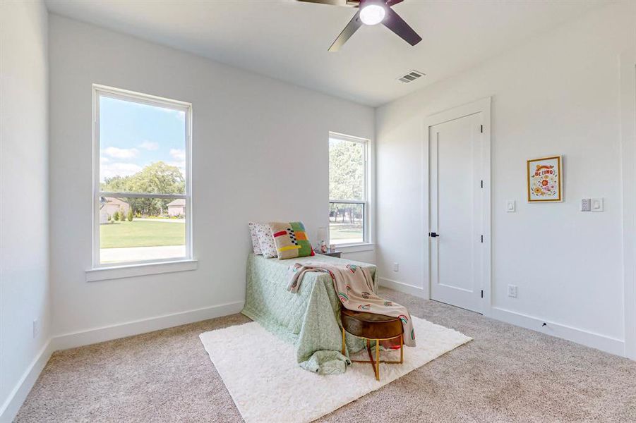 Bedroom featuring light colored carpet, ceiling fan, and multiple windows