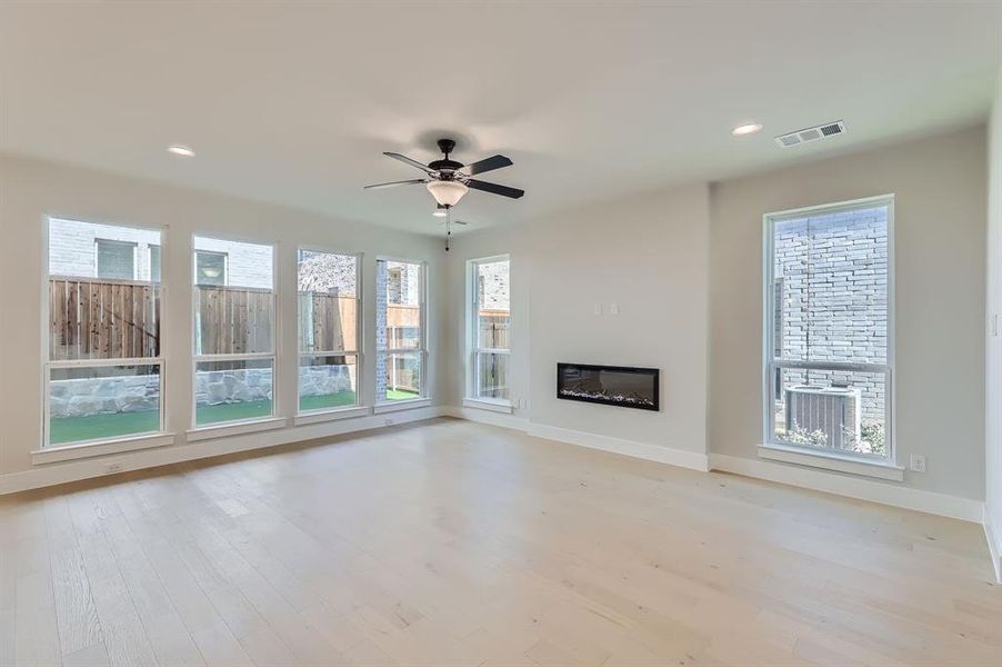 Unfurnished living room featuring ceiling fan, light wood-type flooring, and plenty of natural light