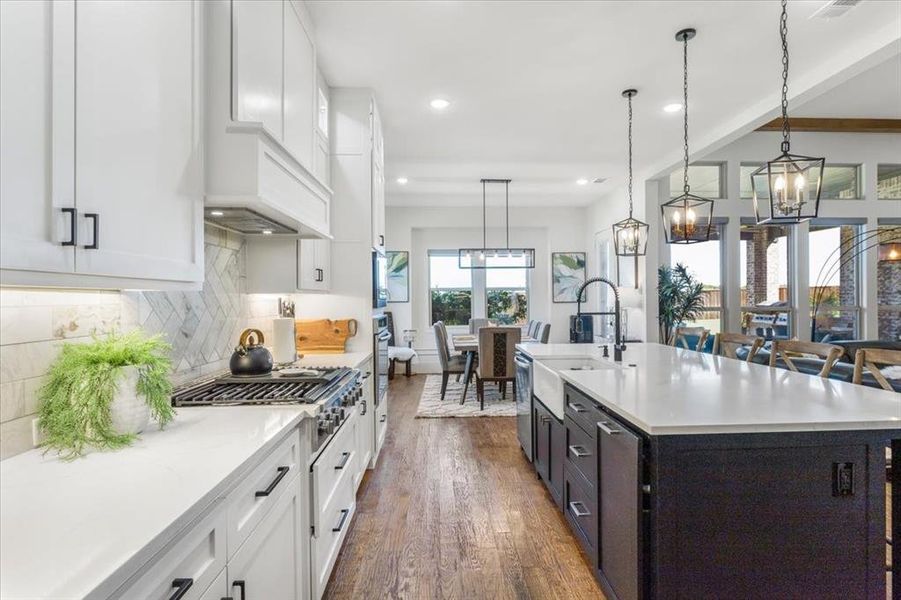 Kitchen featuring pendant lighting, sink, a kitchen island with sink, dark wood-type flooring, and white cabinetry