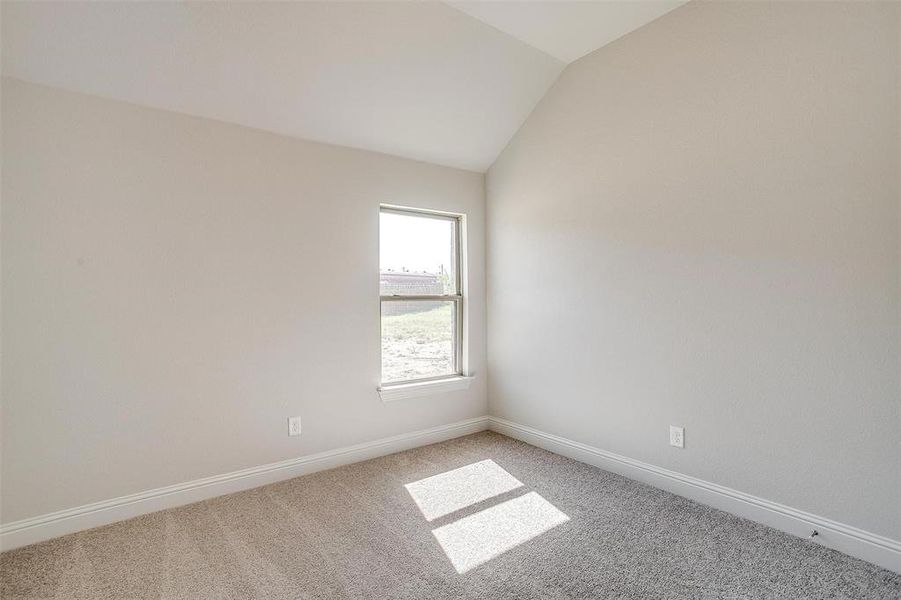 Spare room with vaulted ceiling and carpet floors