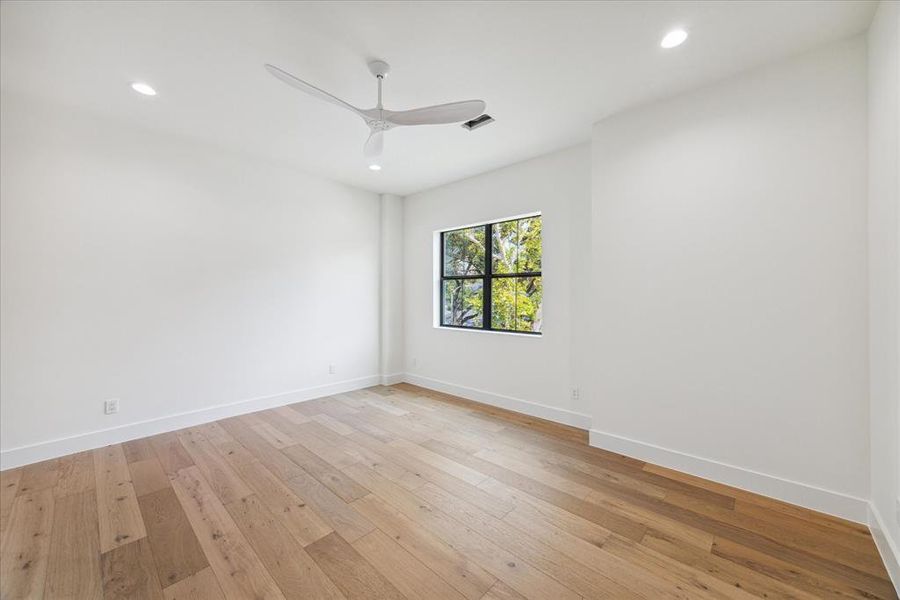 Featuring a window overlooking the front lawn, this bedroom includes a designer ceiling fan and is finished with designer neutral wall paint and recessed LED lighting. It offers access to an ensuite bathroom and includes a large walk-in closet with dual levels for hanging and a built-in dresser.