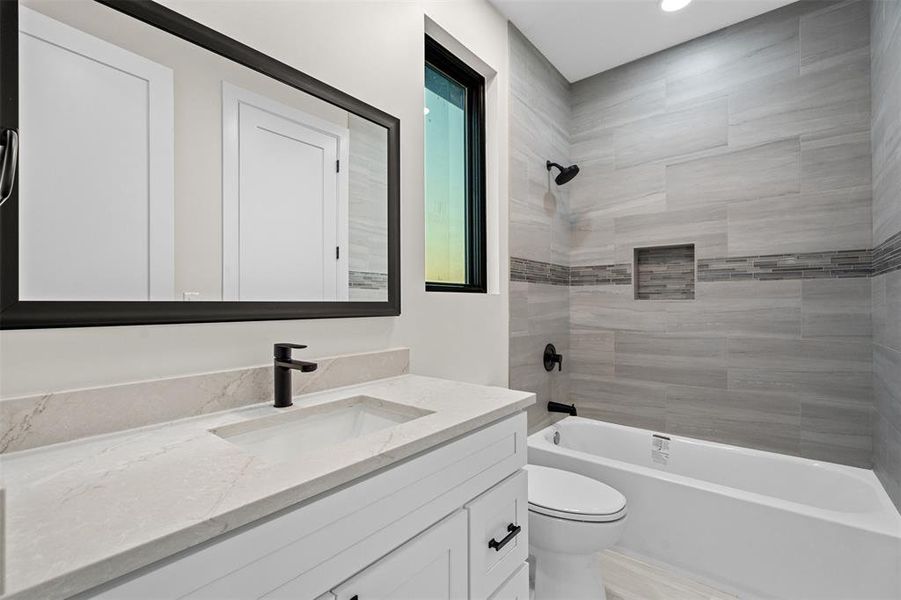 Full bathroom featuring tiled shower / bath, vanity, and toilet