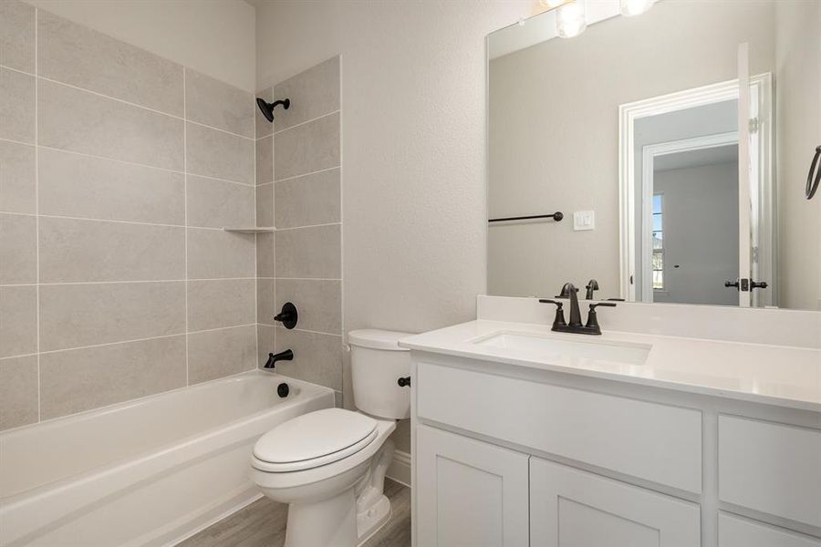 Full bathroom featuring vanity, toilet, tiled shower / bath combo, and hardwood / wood-style floors