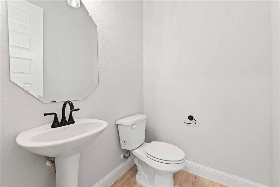 Half Bathroom with hardwood / wood-style flooring and toilet next to game room