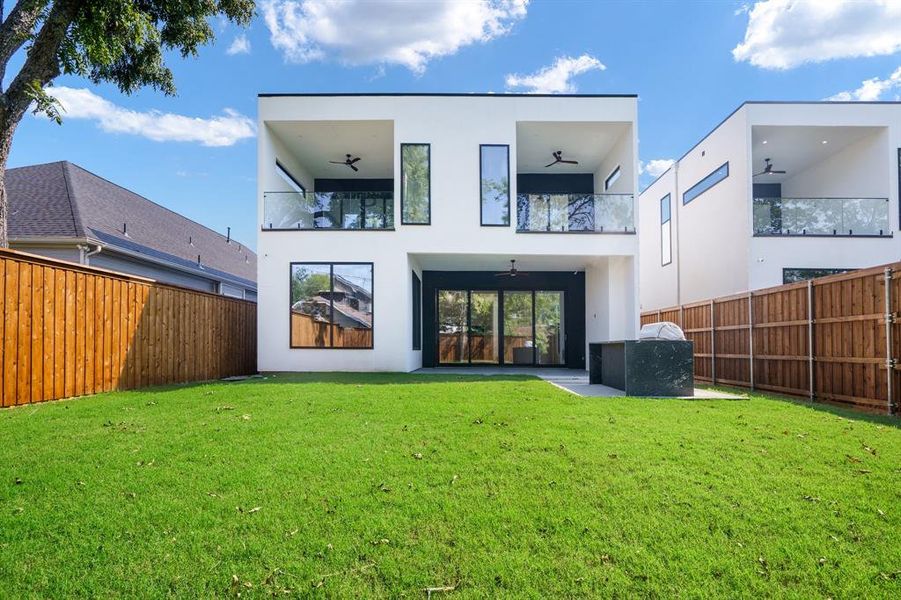 Back of house featuring a yard, a balcony, and ceiling fan